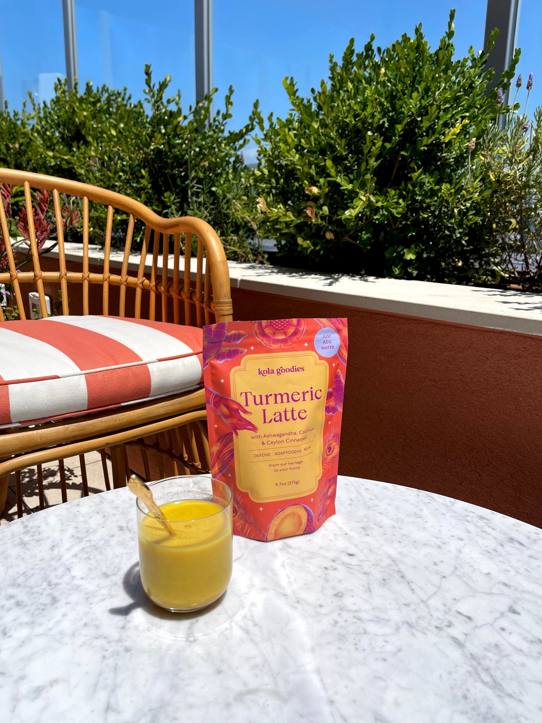 A bag of Kola Goodies Turmeric Latte mix next to a cup of turmeric milk