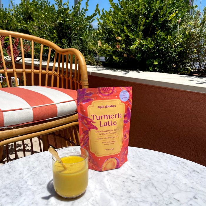 A bag of Kola Goodies Turmeric Latte mix next to a cup of turmeric milk